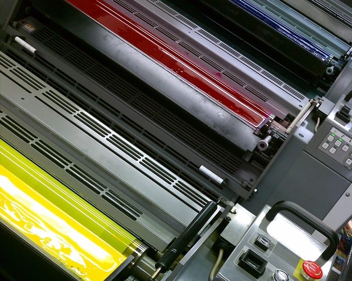 Ink rollers on a printing press, loaded with red and yellow ink
